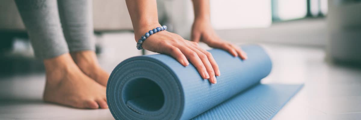 Yoga at home active lifestyle woman rolling exercise mat in living room for morning meditation yoga banner background. Hometraining im Winter