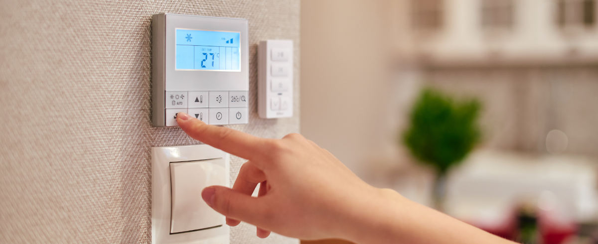 Zeigefinger stellt Thermostat an der Wand ein